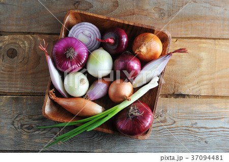 different onion varieties in a wooden plate different onion varieties in a wooden plate 37094481