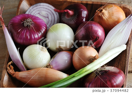 different onion varieties in a wooden plate different onion varieties in a wooden plate 37094482