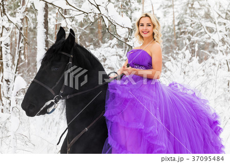 Young woman in long dress riding a horse in winter 37095484