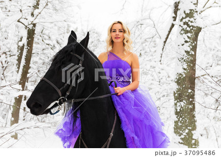 Young woman in long dress riding a horse in winter 37095486