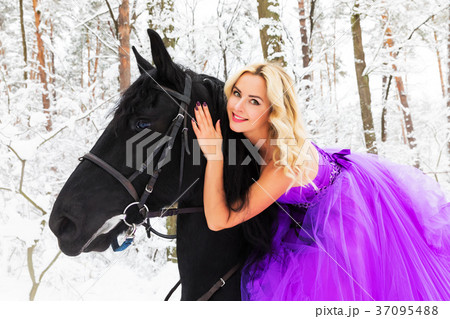 Young woman in long dress riding a horse in winter 37095488