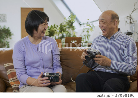 趣味のカメラを持って笑顔で話すシニア夫婦 趣味のカメラを持って笑顔で話すシニア夫婦 37098196