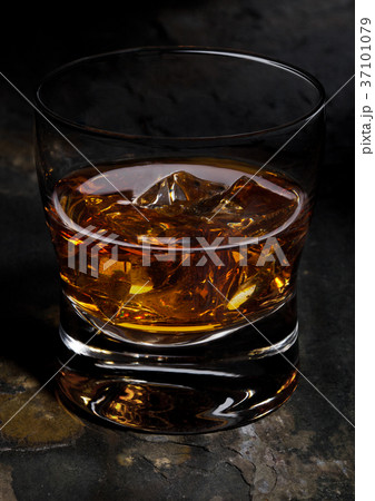 Elegant glass of whiskey with ice cubes on stone Elegant glass of whiskey with ice cubes on stone 37101079