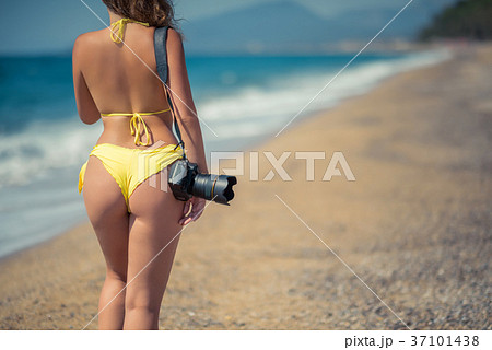 Naked woman in the bikini with camera on the sand - Stock Photo 37101438 