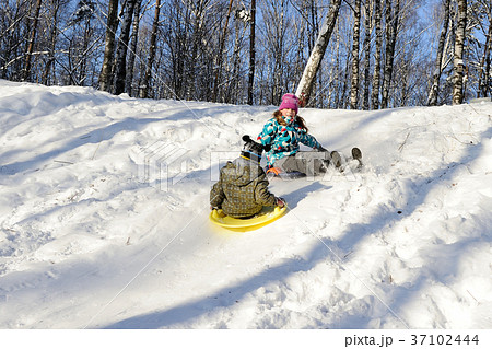 Girl and boy riding with hills on sleds Girl and boy riding with hills on sleds 37102444