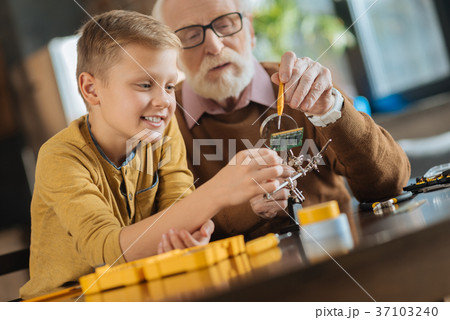 Joyful positive boy working with his grandfather Joyful positive boy working with his grandfather 37103240