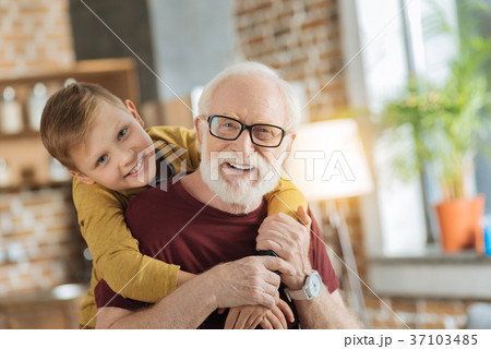 Joyful nice boy hugging his grandfather Joyful nice boy hugging his grandfather 37103485