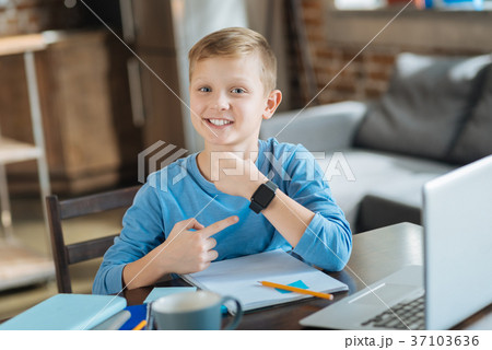 Delighted positive boy pointing at his smartwatch Delighted positive boy pointing at his smartwatch 37103636