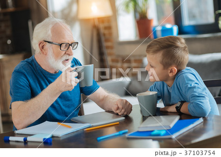 Delighted nice grandfather and grandson having tea Delighted nice grandfather and grandson having tea 37103754