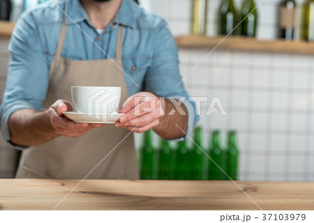 Careful attentive waiter putting a cup of coffee Careful attentive waiter putting a cup of coffee 37103979