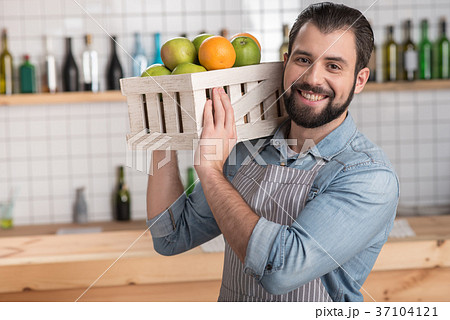 Positive young worker holding a heavy box with 37104121