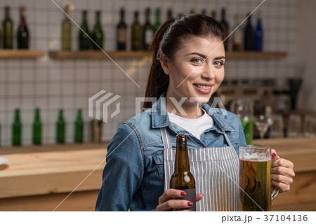 Lovely cheerful waitress standing with beer and 37104136