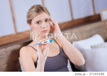 Upset sick young woman showing thermometer 37104180