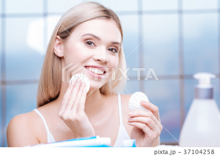 Lively woman cleaning her skin with cotton pads Lively woman cleaning her skin with cotton pads 37104258