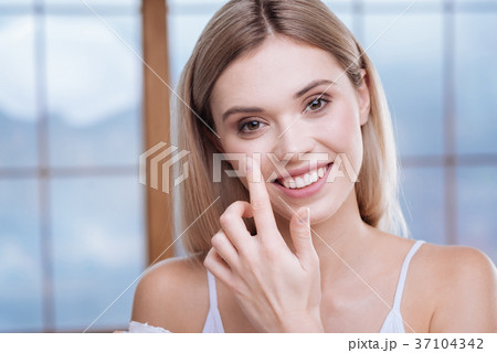 Adorable woman applying cream to her cheeks Adorable woman applying cream to her cheeks 37104342