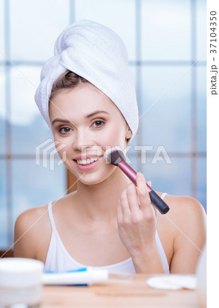 Cheerful woman applying powder and smiling 37104350
