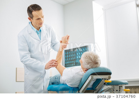 Positive cheerful therapist checking his patients Positive cheerful therapist checking his patients 37104760