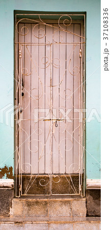 White door behind metal grate on blue wall with stone steps White door behind metal grate on blue wall with stone steps 37108336