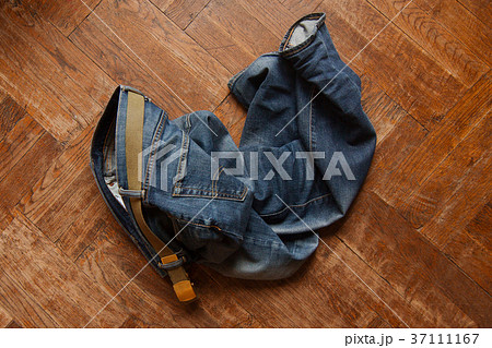 blue jeans thrown on wooden floor 37111167
