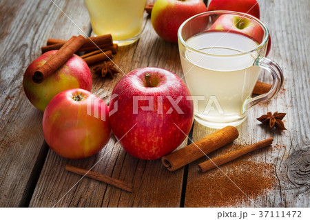 Apples, cider and cinnamon on old wooden table 37111472