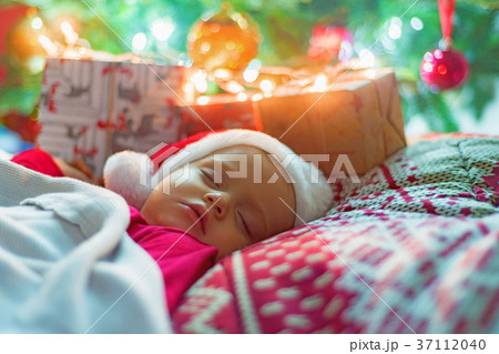 Cute little baby girl sleeping near Christmas tree 37112040