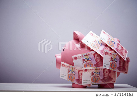 豚の貯金箱と人民元紙幣の写真素材