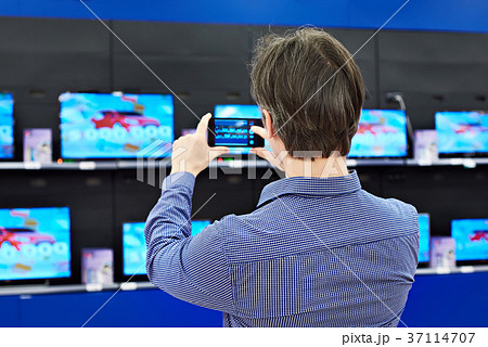 Man shoots with smartphone TVs in shop Man shoots with smartphone TVs in shop 37114707