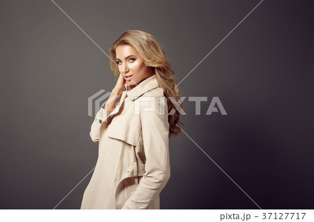 Attractive young woman in beige coat looking at Attractive young woman in beige coat looking at 37127717