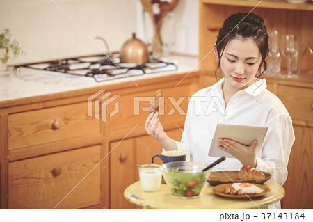 朝ごはんを食べながらニュースを見る女の子 37143184