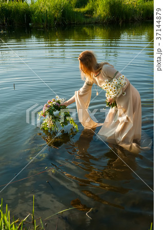 Attractive woman lowers wreath in water Attractive woman lowers wreath in water 37144879