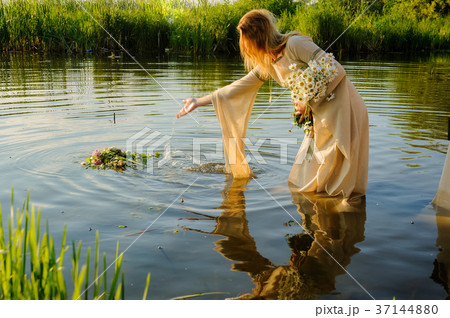 Attractive woman lowers wreath in water Attractive woman lowers wreath in water 37144880