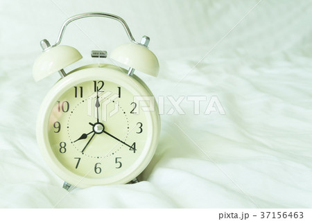 Closeup alarm clock on white bed in bedroom 37156463