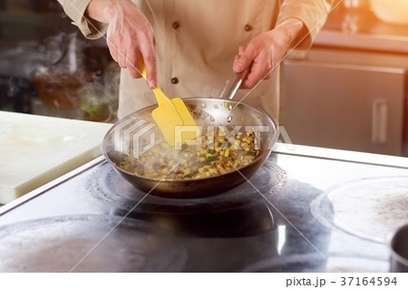 Hands of chef stirring stewing vegetables. 37164594