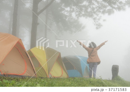 tourist raise hand with happiness near tent in mist & fog. camping in forest. people, travel, vacation concept 37171583