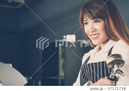 small business owner standing at counter in coffee shop. female barista wearing apron smiling at bar in cafe. food service, restaurant concept. small business owner standing at counter in coffee shop. female barista wearing apron smiling at bar in cafe. food service, restaurant concept. 37171738
