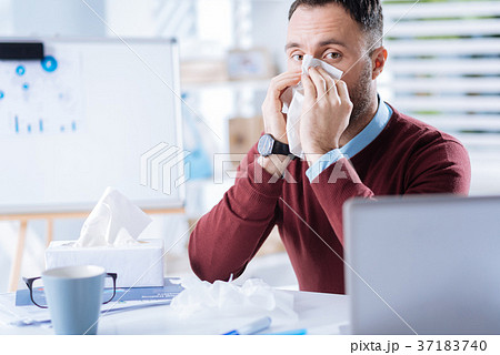 Young man looking thoughtful while blowing his 37183740