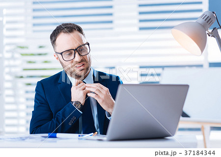 Upset bearded worker looking at the screen while Upset bearded worker looking at the screen while 37184344