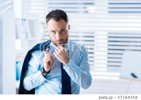Confident young specialist touching his chin while Confident young specialist touching his chin while 37184358
