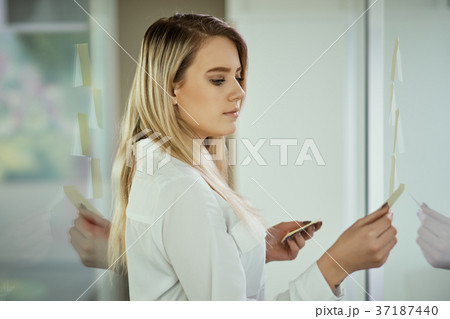 young girl is holding yellow sticky notes in a glass office young girl is holding yellow sticky notes in a glass office 37187440