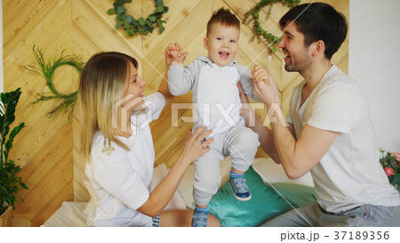 A young family with little son play on bed in the A young family with little son play on bed in the 37189356