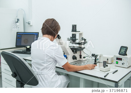 medical researcher looking through microscop 37196871