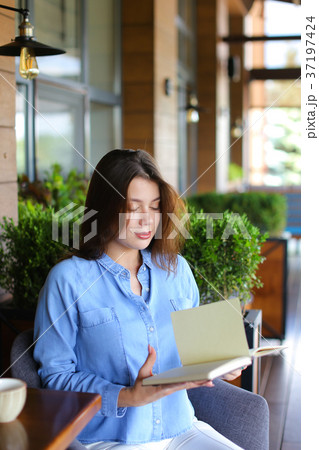 Beautiful girl reading diary at cafe  . 37197424