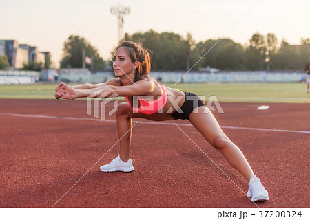 Runner woman stretching legs warming up before 37200324