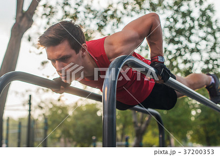 Fit young man doing push ups on horizontal bar 37200353