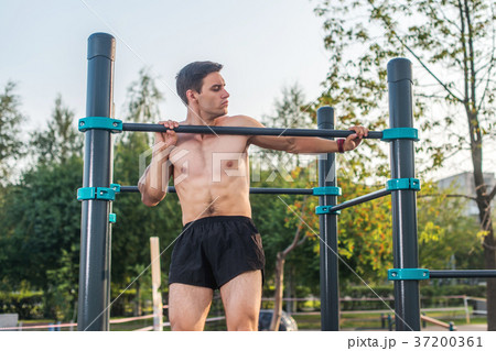Young male athlete doing chin-up exercises in the 37200361