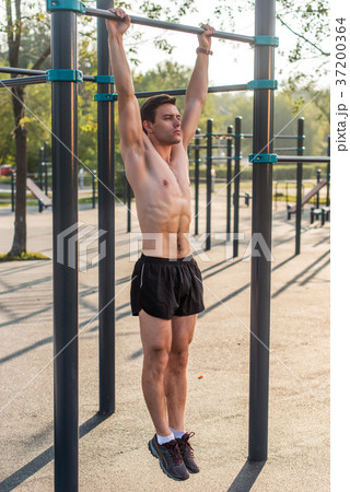 Young muscular athlete doing pull-up exercises 37200364