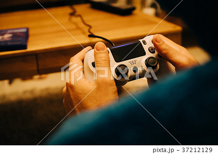 部屋でゲームをする男性の手元の写真素材