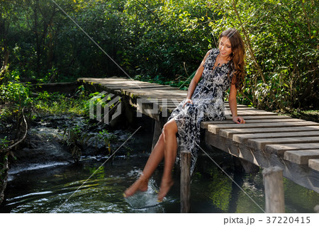 Pretty girl sits on wooden bridge Pretty girl sits on wooden bridge 37220415