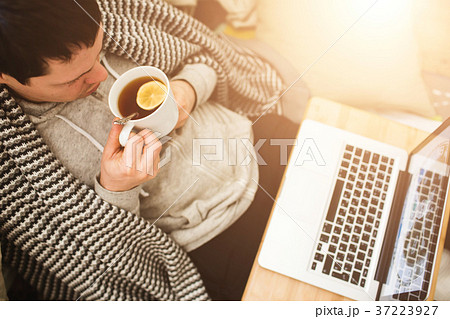 Young man laying in bad with laptop and cup of tea Young man laying in bad with laptop and cup of tea 37223927