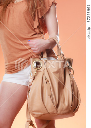 Girl in shorts holding beige bag orange background 37223961